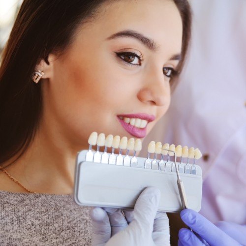 Woman's smile compared with veneers color options during cosmetic dentistry treatment