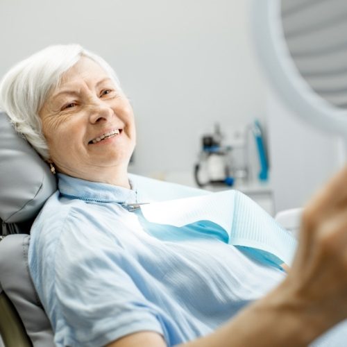 Woman looking at smile after tooth replacement with dental implants