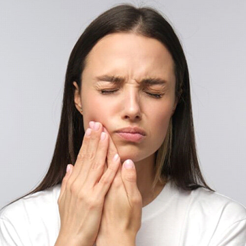 grimacing woman holding her hands on her cheeks