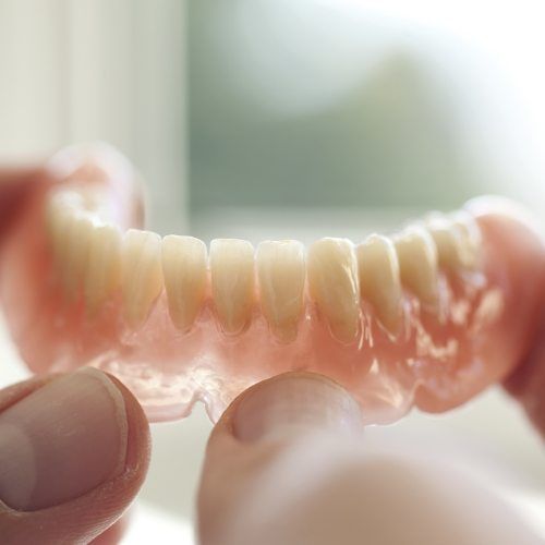 Hand holding a denture restoration